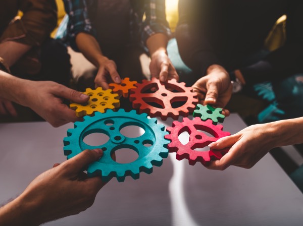 colorful gears being held by teammates in a circle
